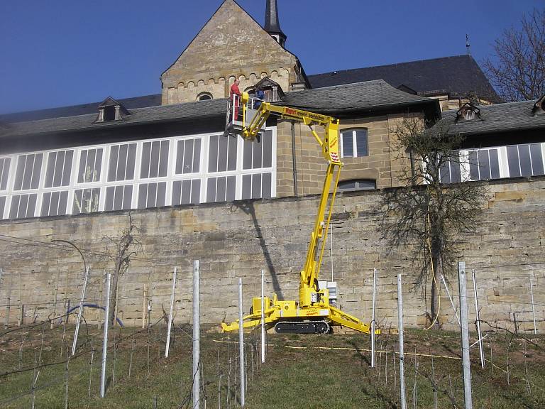 Wartungarbeiten an einer schwer zugänglichen Fassade an einem steilen Abhang mithilfe einer Kettenteleskoparbeitsbühne.