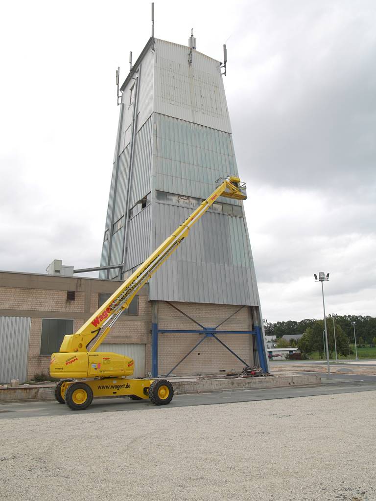 Wartungsarbeiten an der Fassade eines Industrieturms mithilfe einer Teleskoparbeitsbühne.
