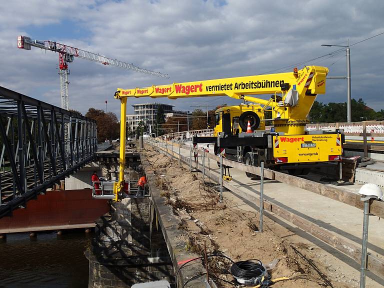 Wagert LKW-Arbeitsbühne steht auf einer Brücke während im ausgefahrenen Arbeitsbühnenkorb Arbeiten am Rand der Brücke durchgeführt werden.